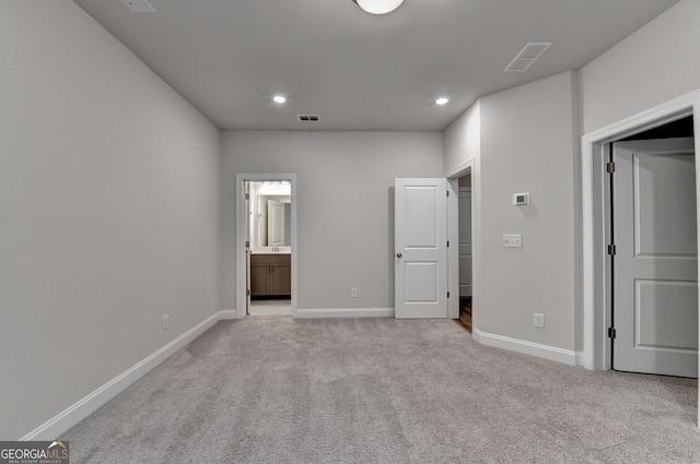 unfurnished bedroom with ensuite bathroom and light colored carpet