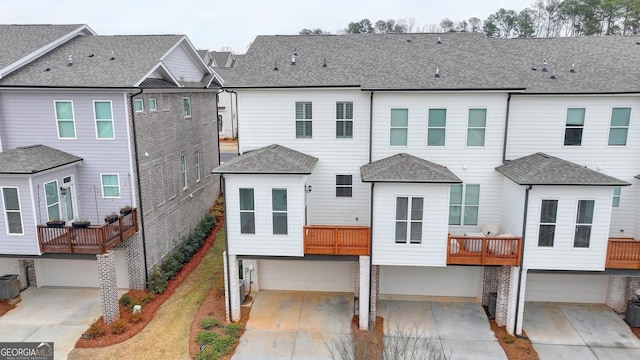 rear view of property with central AC unit and a garage