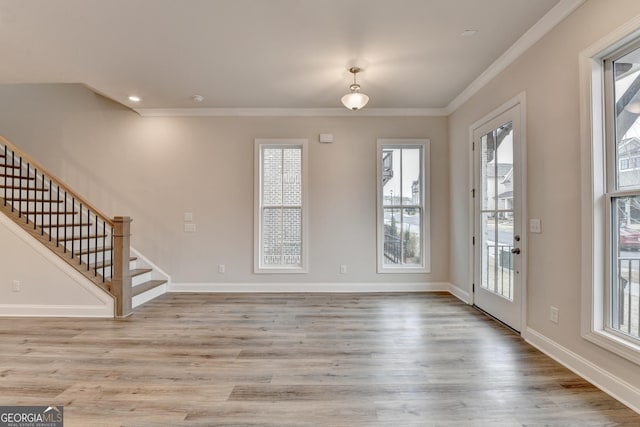 interior space featuring light wood-type flooring, a wealth of natural light, and crown molding