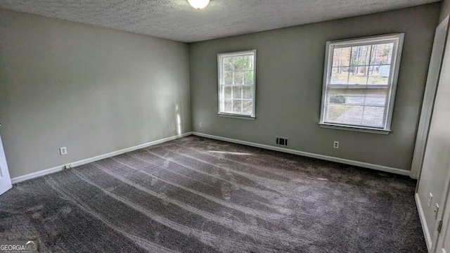 carpeted empty room with a textured ceiling