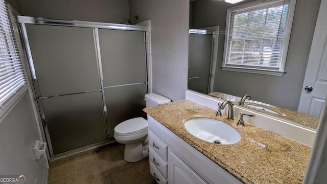 bathroom featuring vanity, a shower with shower door, and toilet