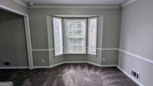 empty room featuring dark carpet, crown molding, a textured ceiling, and a wealth of natural light