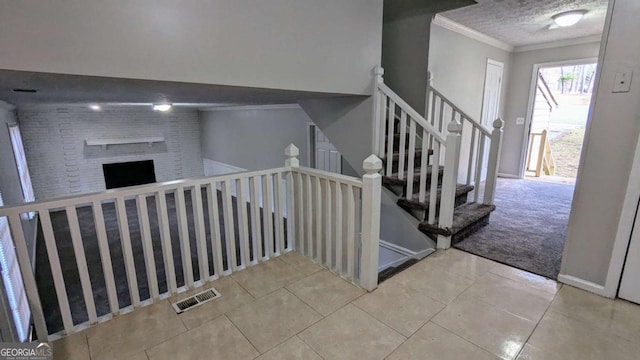 staircase featuring carpet, a textured ceiling, a fireplace, and ornamental molding