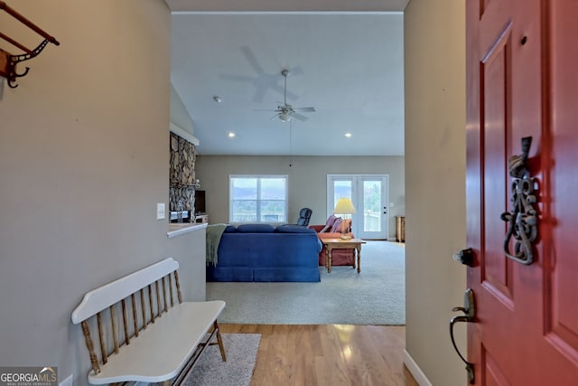 foyer entrance with ceiling fan, vaulted ceiling, and light wood-type flooring