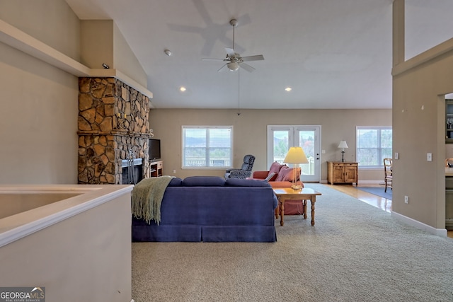 living room featuring a healthy amount of sunlight, a fireplace, high vaulted ceiling, and light carpet