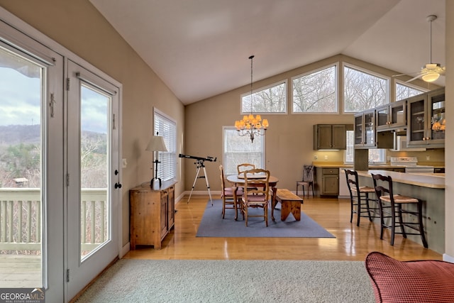 dining room featuring ceiling fan with notable chandelier, light hardwood / wood-style floors, and vaulted ceiling