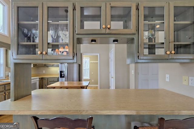 kitchen featuring gray cabinetry, a breakfast bar, stainless steel fridge, and white stove