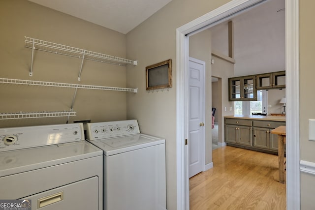 laundry area featuring washing machine and dryer and light hardwood / wood-style floors