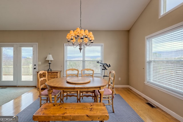 dining room featuring an inviting chandelier, a healthy amount of sunlight, vaulted ceiling, and light hardwood / wood-style floors