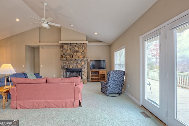 carpeted living room featuring ceiling fan, a stone fireplace, and vaulted ceiling