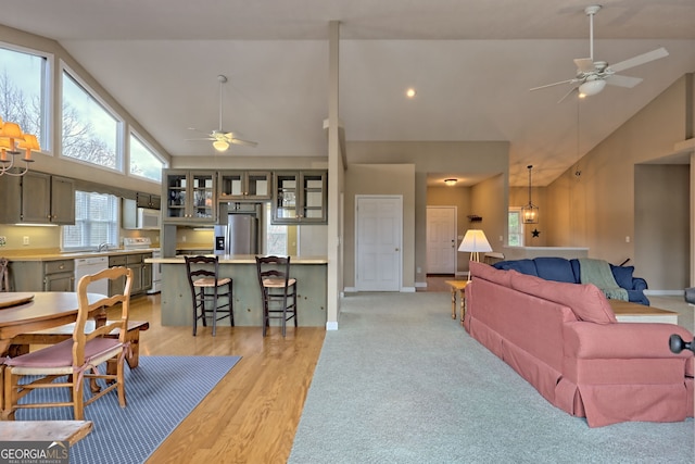 living room featuring light hardwood / wood-style floors, high vaulted ceiling, and ceiling fan