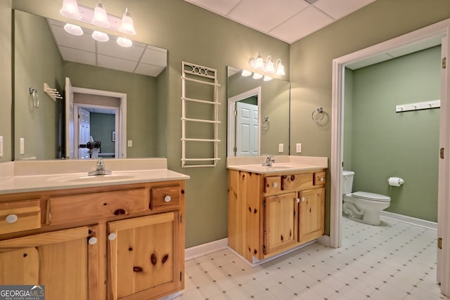 bathroom with vanity, toilet, and a drop ceiling