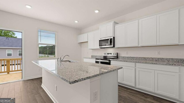 kitchen with white cabinetry, a center island with sink, dark wood-type flooring, and appliances with stainless steel finishes