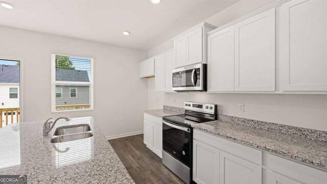 kitchen featuring white cabinets, sink, dark hardwood / wood-style floors, light stone countertops, and appliances with stainless steel finishes