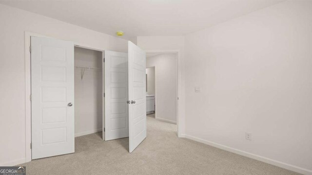 unfurnished bedroom featuring light colored carpet and a closet