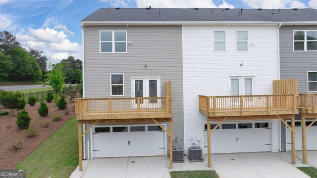 rear view of property featuring central AC and a garage