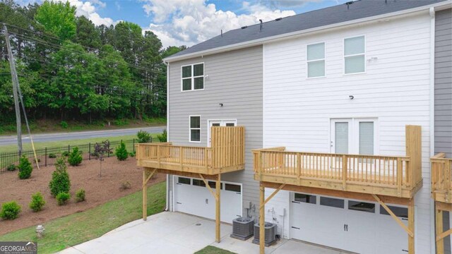 back of property with central AC unit and a garage