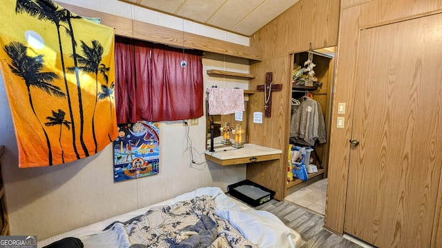 bedroom featuring light wood-type flooring and wood walls