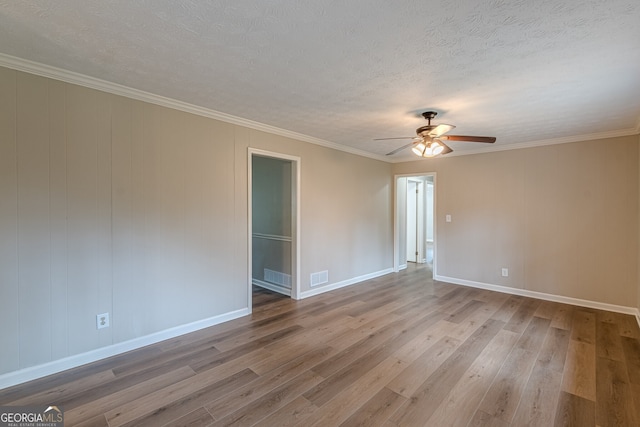 empty room featuring ceiling fan, hardwood / wood-style flooring, ornamental molding, and a textured ceiling