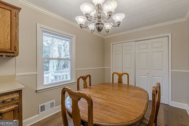 dining area with dark hardwood / wood-style flooring, ornamental molding, and a chandelier