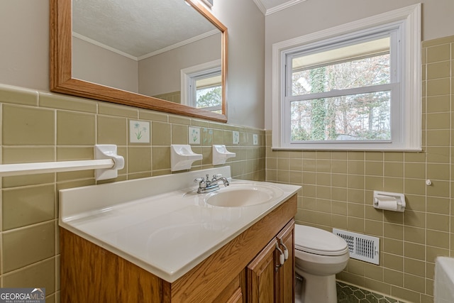 bathroom featuring toilet, tile walls, ornamental molding, vanity, and tile patterned flooring