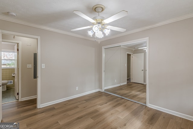 unfurnished bedroom featuring wood-type flooring, ornamental molding, a closet, and ceiling fan