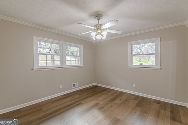 empty room with wood-type flooring, ornamental molding, and a textured ceiling