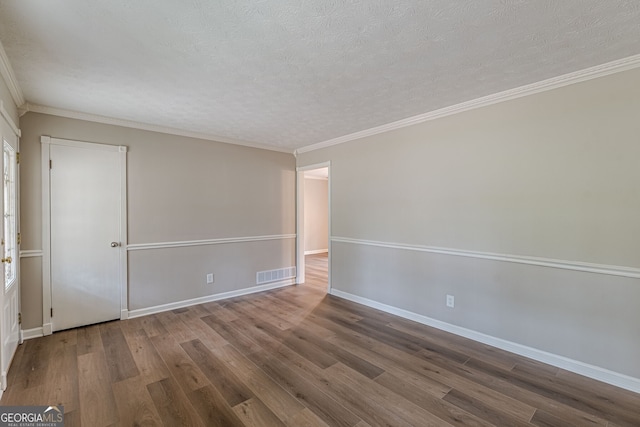 spare room featuring crown molding, wood-type flooring, and a textured ceiling