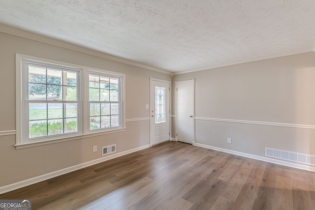 unfurnished room featuring crown molding, a textured ceiling, and light wood-type flooring