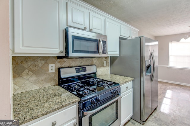 kitchen with light stone countertops, stainless steel appliances, a notable chandelier, backsplash, and white cabinets