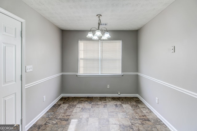 unfurnished room with a textured ceiling and an inviting chandelier