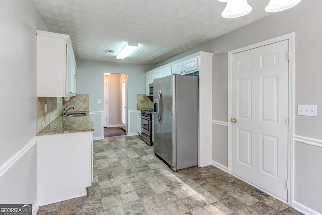 1624 Graystone Dr, Hampton, GA 30228 - kitchen with stainless steel appliances, backsplash, white cabinets, light stone countertops, and a textured ceiling