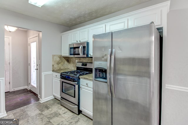 kitchen with tasteful backsplash, light stone counters, white cabinets, and stainless steel appliances