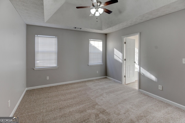 carpeted spare room featuring ceiling fan, a textured ceiling, and a tray ceiling