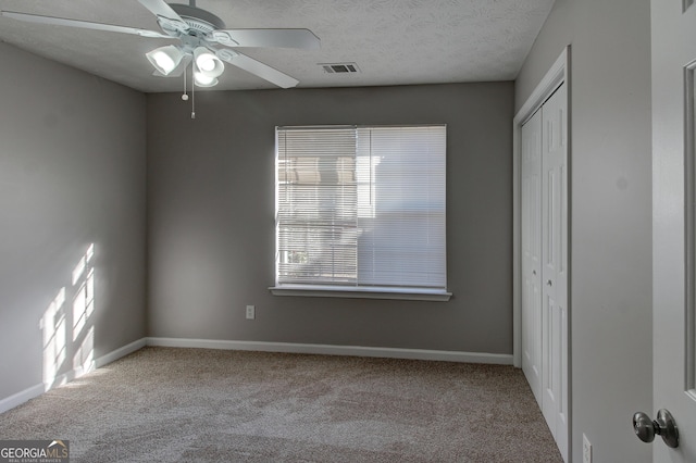 empty room with carpet flooring, a textured ceiling, and ceiling fan