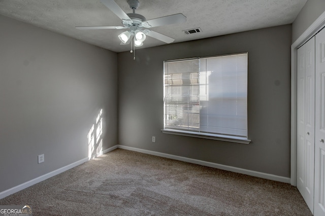 unfurnished bedroom with a textured ceiling, a closet, ceiling fan, and light colored carpet