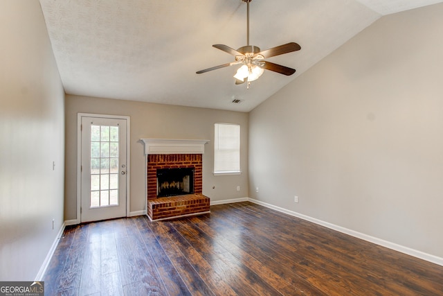 unfurnished living room with a brick fireplace, ceiling fan, dark wood-type flooring, and vaulted ceiling