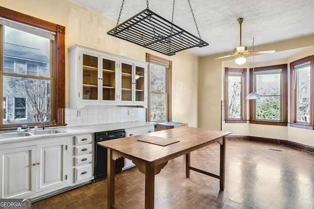 kitchen featuring sink, black dishwasher, backsplash, a textured ceiling, and white cabinets