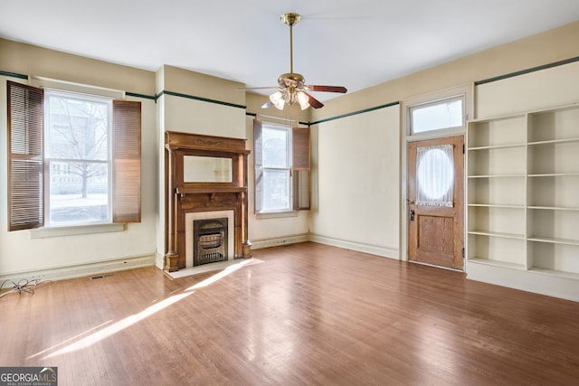 unfurnished living room featuring hardwood / wood-style flooring, ceiling fan, and a wealth of natural light