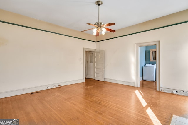 spare room with washer / clothes dryer, light hardwood / wood-style flooring, and ceiling fan