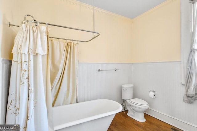 bathroom featuring a tub to relax in, crown molding, toilet, and hardwood / wood-style flooring