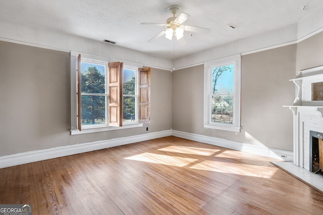 unfurnished living room with ceiling fan, a fireplace, and light wood-type flooring