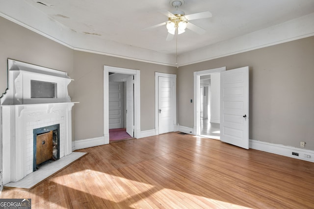 unfurnished living room featuring ceiling fan, wood-type flooring, and a fireplace