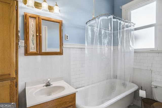 full bathroom featuring vanity, a healthy amount of sunlight, shower / bathtub combination with curtain, and tile walls