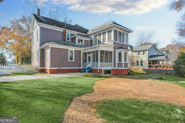 view of front facade with a sunroom and a front lawn