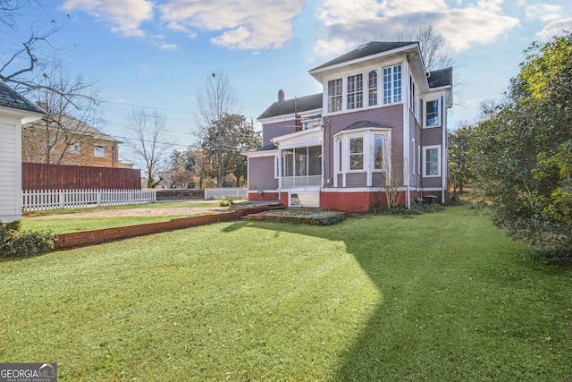 back of house with a lawn and a sunroom