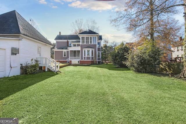 rear view of property featuring a lawn and a sunroom