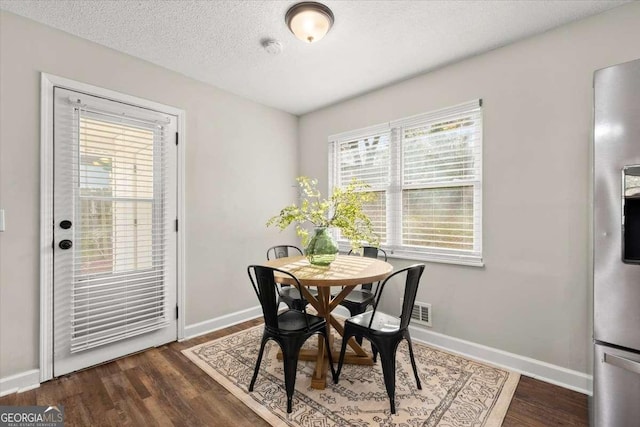 dining room with dark hardwood / wood-style floors and a textured ceiling