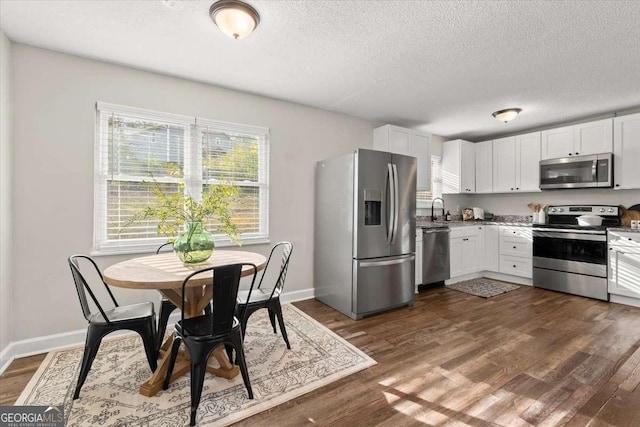 kitchen with white cabinets, dark hardwood / wood-style flooring, and appliances with stainless steel finishes