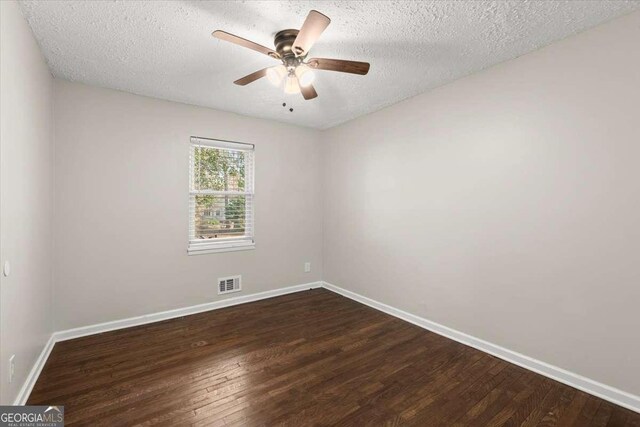 empty room featuring ceiling fan, dark wood-type flooring, and a textured ceiling